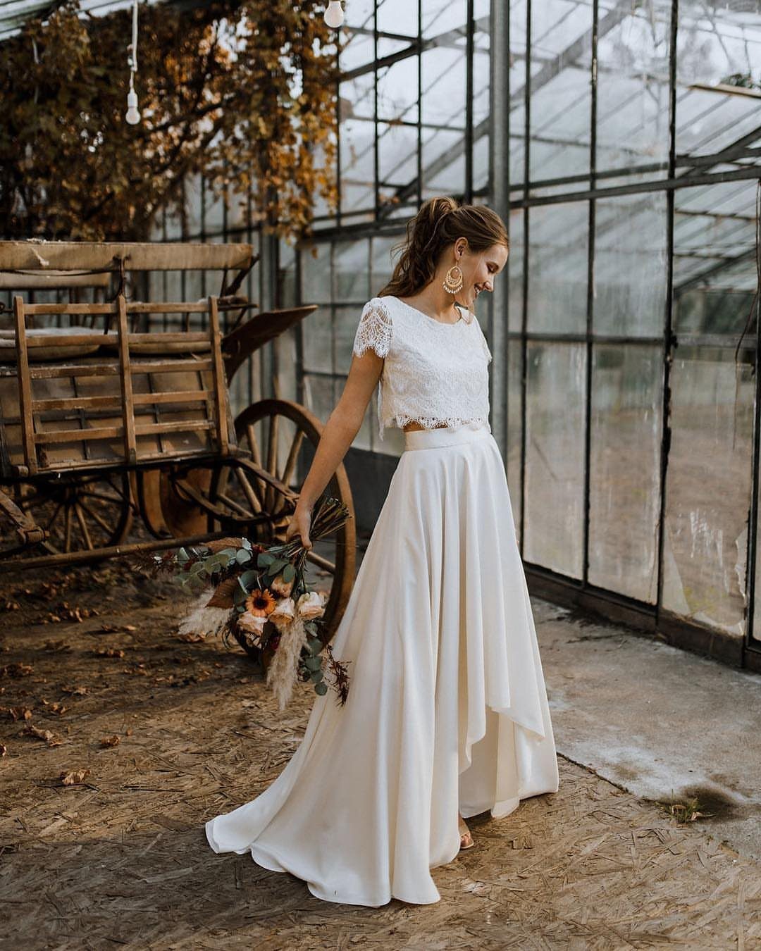 Boho Wedding Dress Looks: 8 Ideas from Lace to Chiffon 5 Woman wearing a white lace crop top and long skirt in a greenhouse.