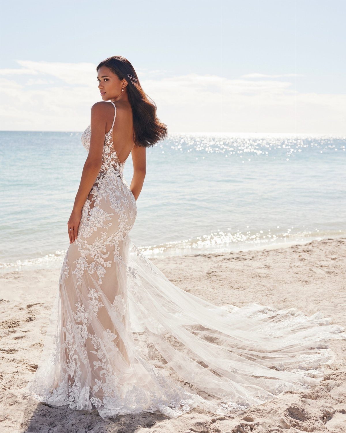 Boho Wedding Dress Looks: 8 Ideas from Lace to Chiffon 1 Woman in a white lace boho wedding dress standing on a sunny beach
