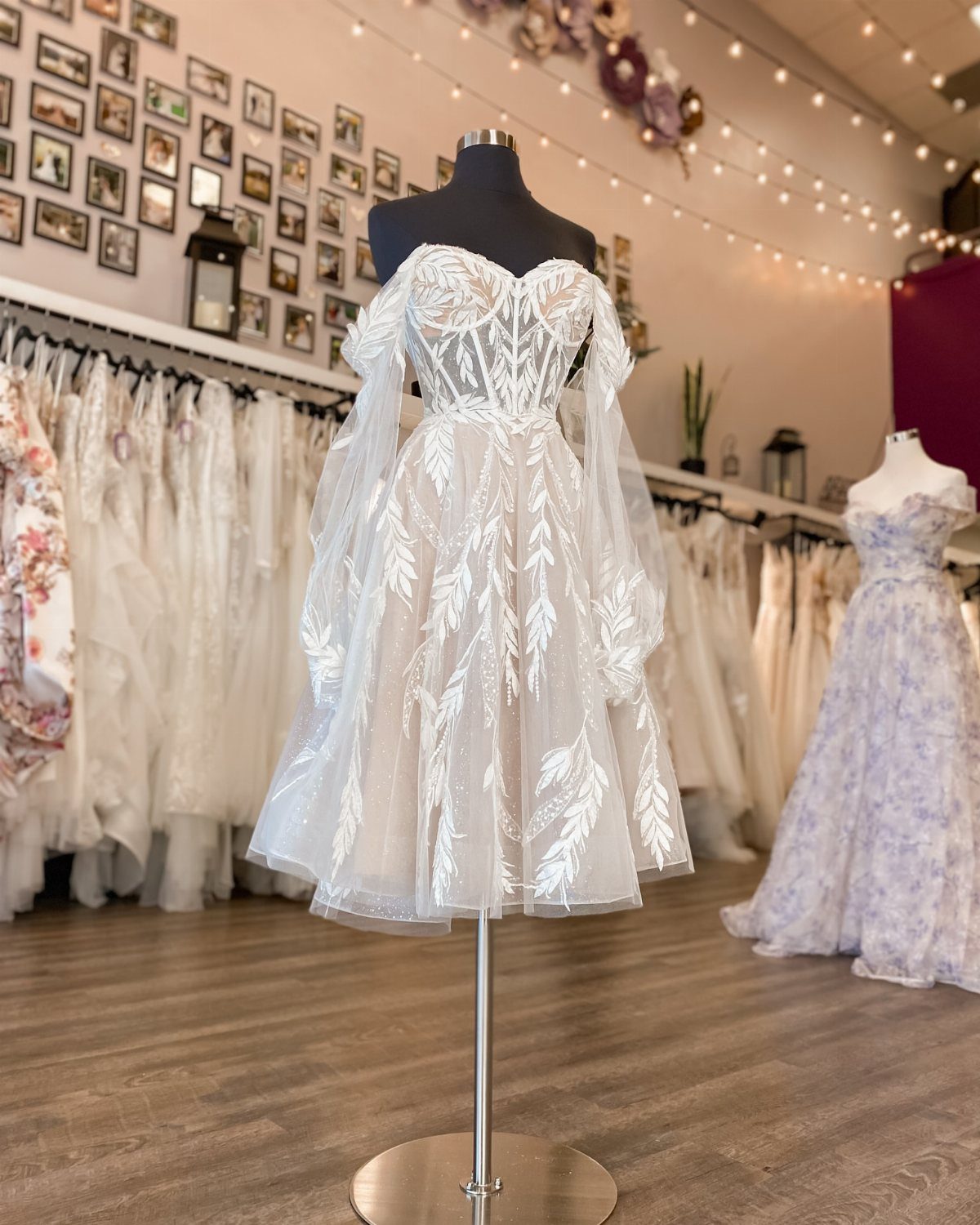 Boho Wedding Dress Looks: 8 Ideas from Lace to Chiffon 4 Short white boho wedding dress with lace embroidery and sheer sleeves on a mannequin.