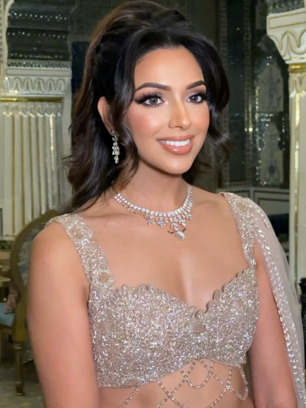 Bride Reception Dress: 17 Ideas for Your Second Look 3 Woman in a sparkling champagne beaded crop top and diamond necklace posing indoors.