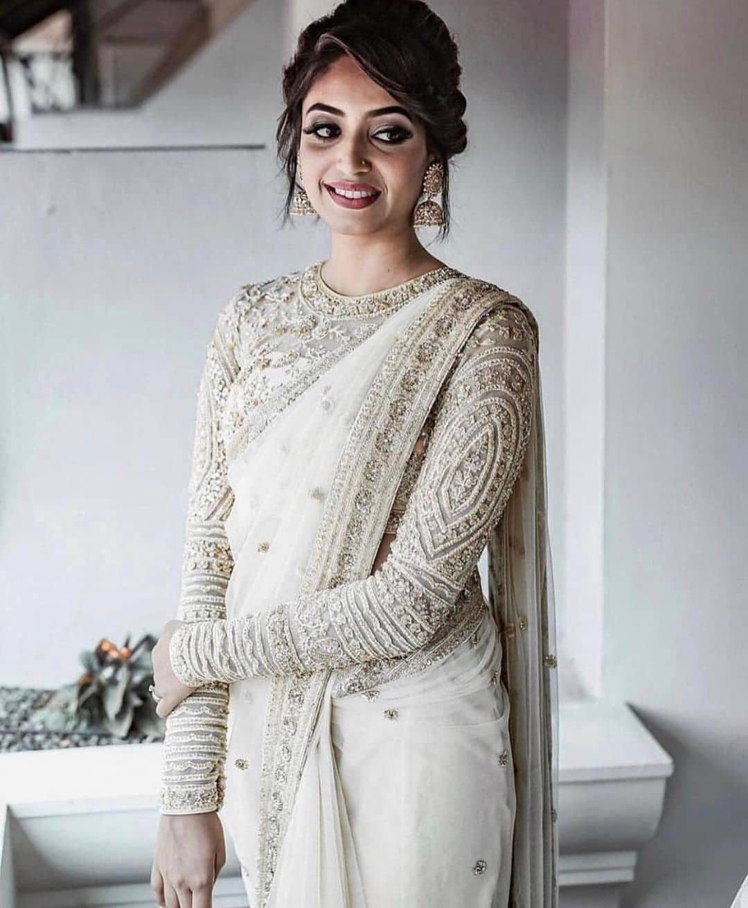 Bride Reception Dress: 17 Ideas for Your Second Look 4 Woman in white and gold embroidered bridal saree with detailed long sleeves.