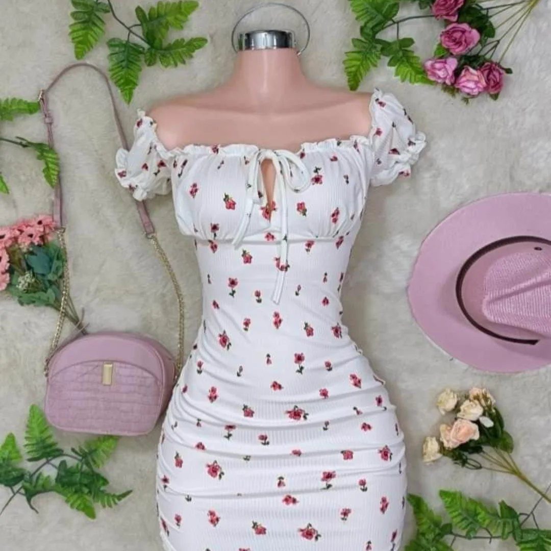 White dress with red floral print on a mannequin with pink accessories.