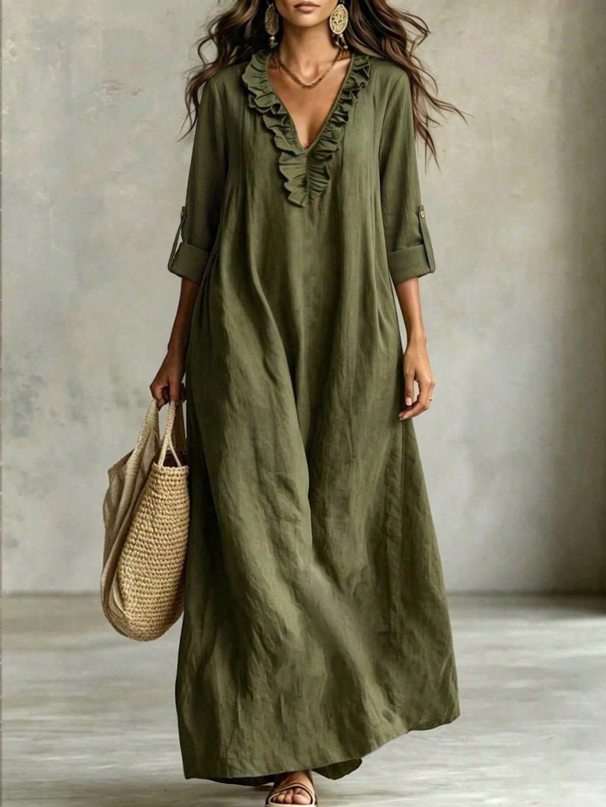 Woman wearing an olive green ruffled caftan dress and carrying a straw tote bag.