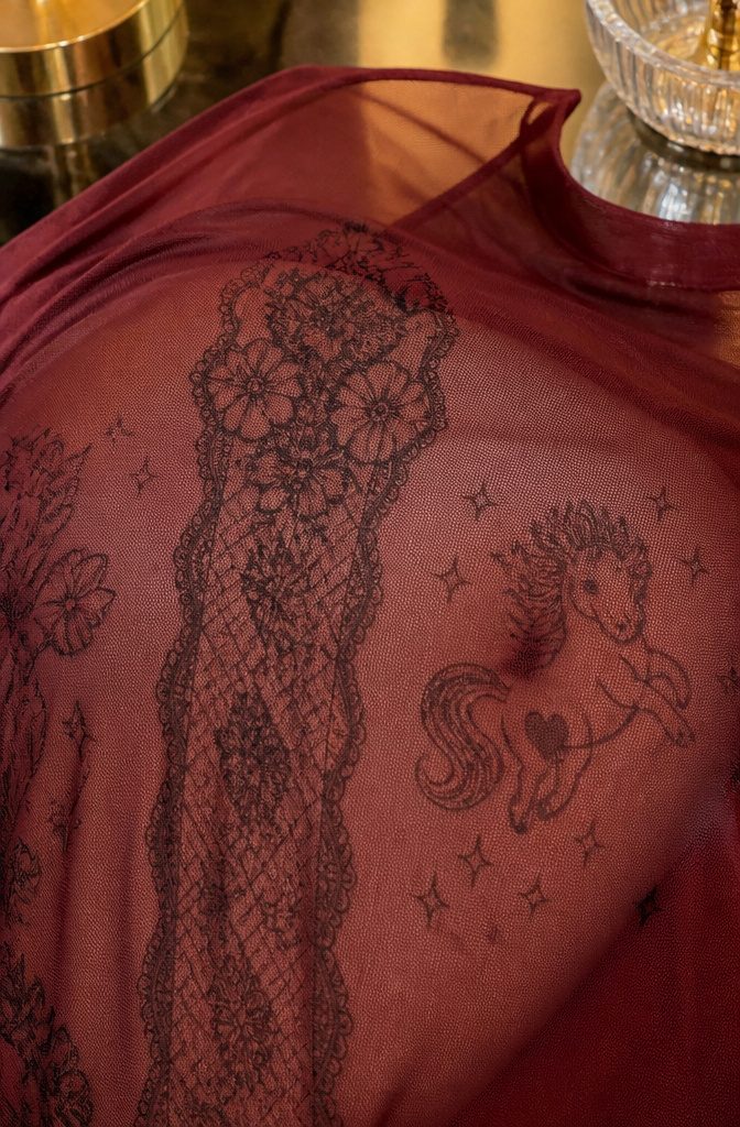 Close-up of Chappell Roan's temporary tattoos on burgundy mesh fabric.