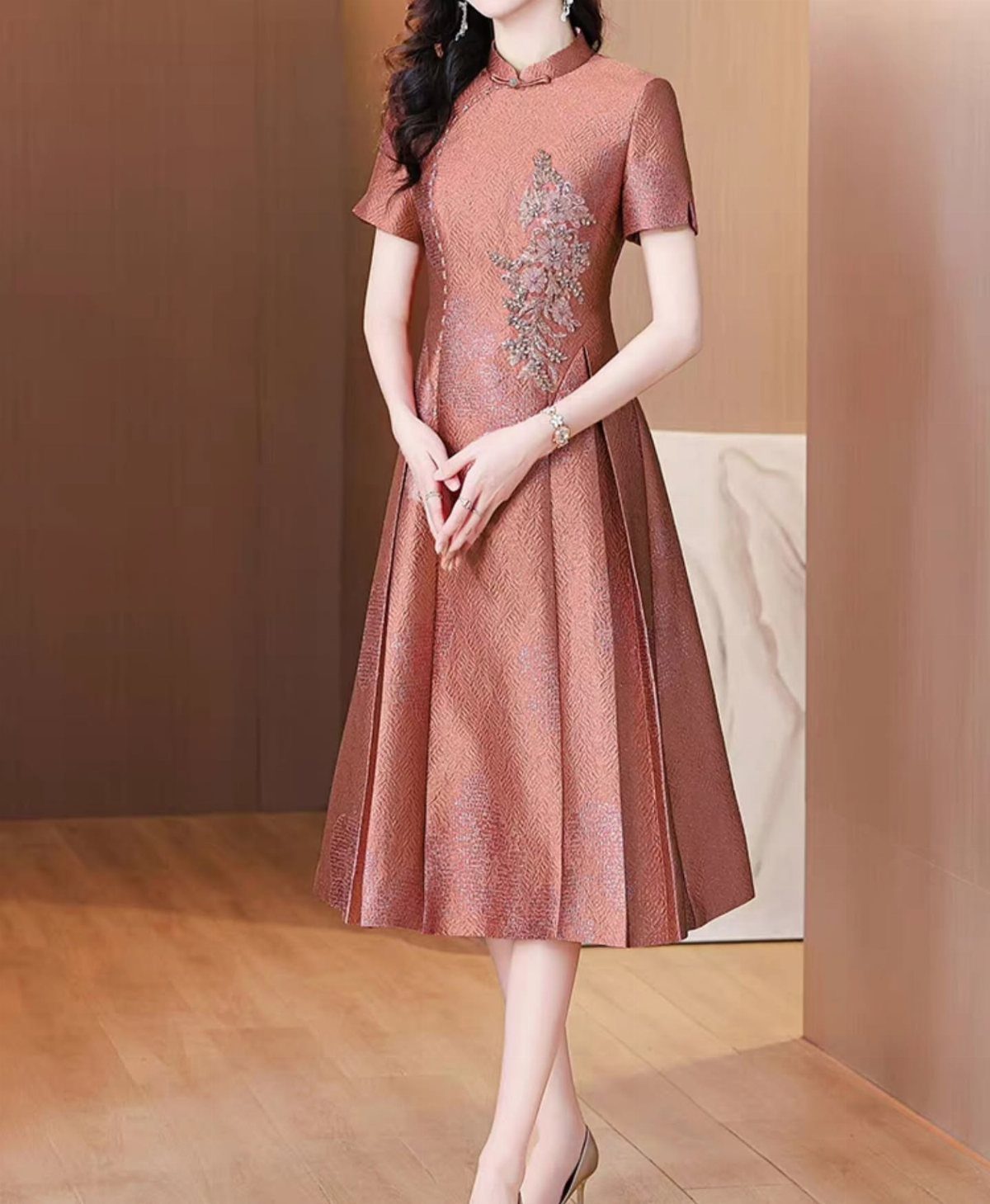 Woman in a rose-gold metallic dress with mandarin collar and floral embroidery.