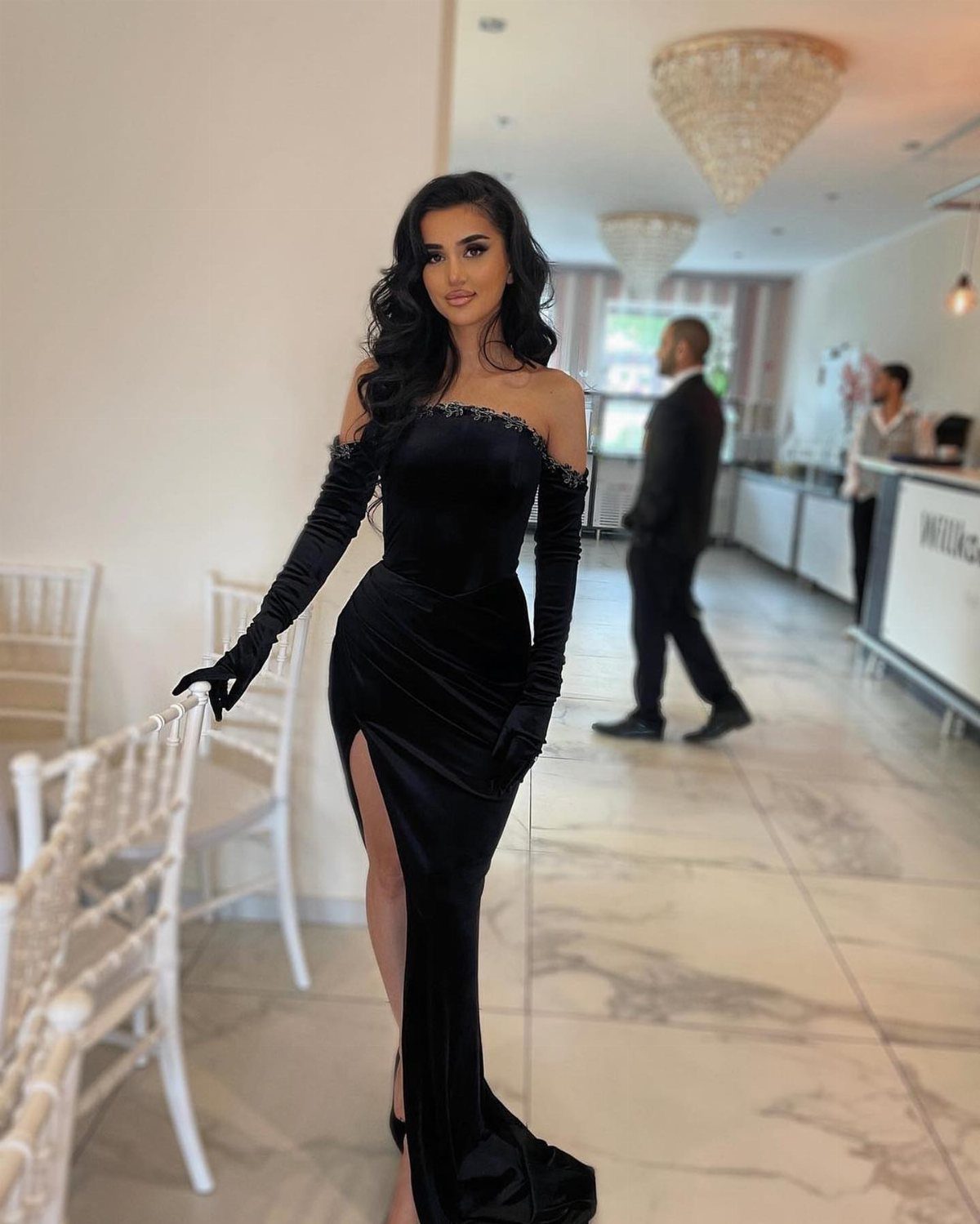 Woman wearing a black velvet off-the-shoulder gown with long matching opera gloves.