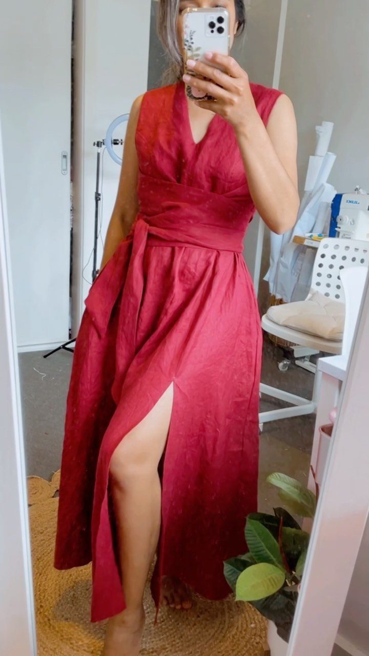 Woman in a red sleeveless wrap dress with a high leg slit.