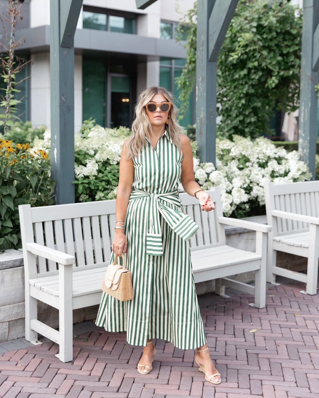 Woman in a green and white striped belted midi dress standing outdoors.