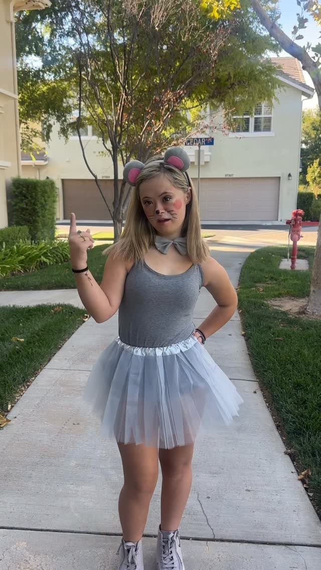 Woman dressed as a mouse with grey top, blue tutu, and mouse ears.