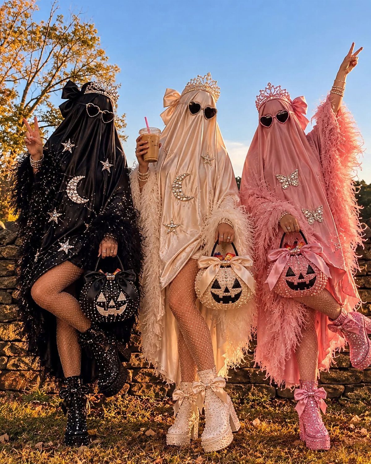 Three people in glamorous satin ghost costumes in black, cream, and pink colors.