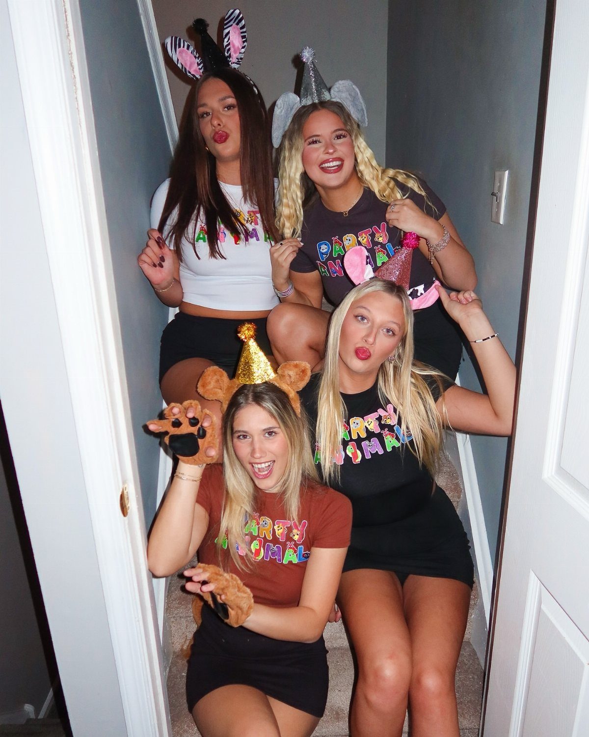 Three women wearing Party Animal t-shirts and animal headbands posing on a staircase.