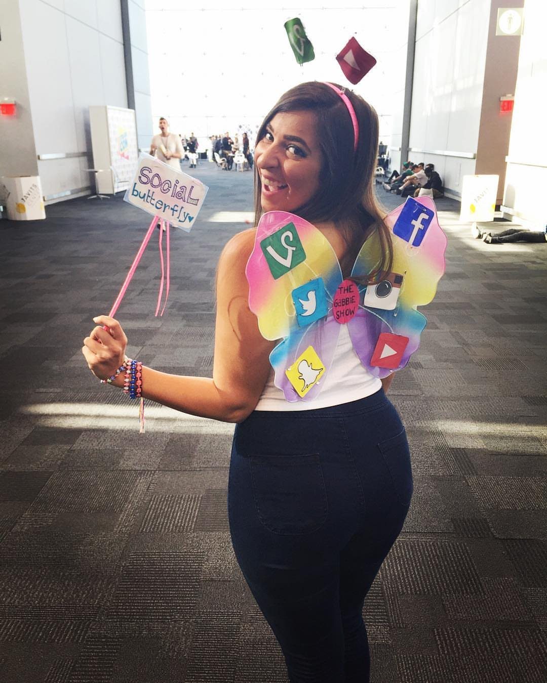 Woman wearing social media icon butterfly wings and holding a Social Butterfly sign.