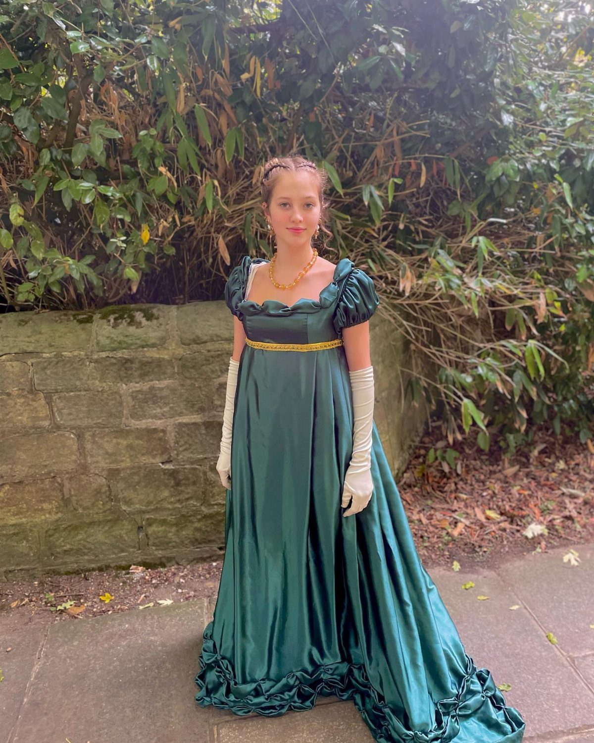 Woman in a green satin eighties style prom dress with white opera gloves