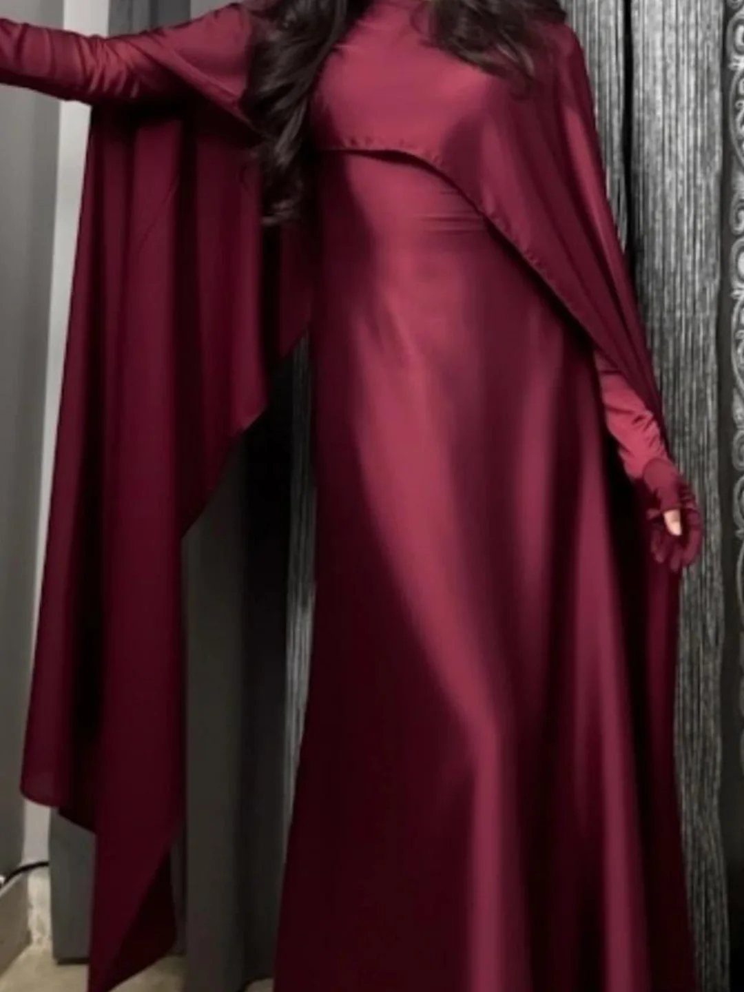 Elegant Dresses for Wedding Guests Over 50 (8 Refined Styles) 8 Woman wearing a long burgundy satin gown with a matching cape overlay