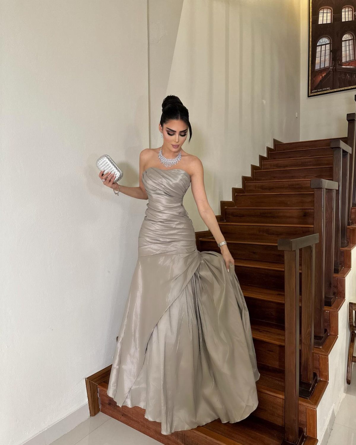 Woman in a champagne satin mermaid gown standing on a wooden staircase.