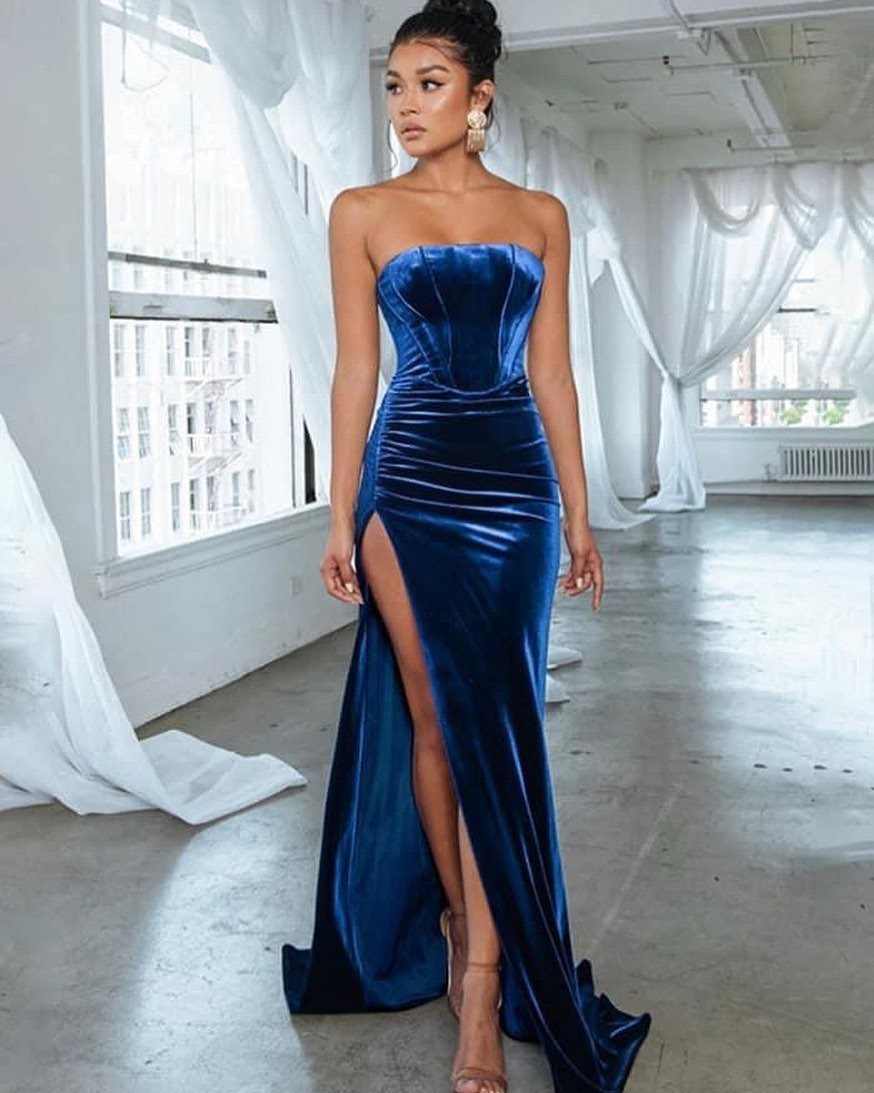 Woman in a strapless royal blue velvet evening gown with a high thigh slit.