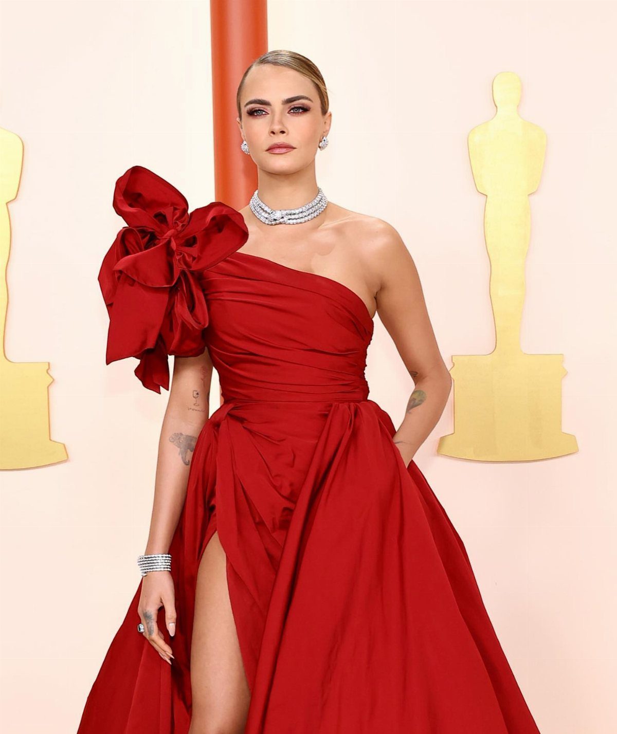 Woman in a red one-shoulder Elie Saab gown with a large bow shoulder.