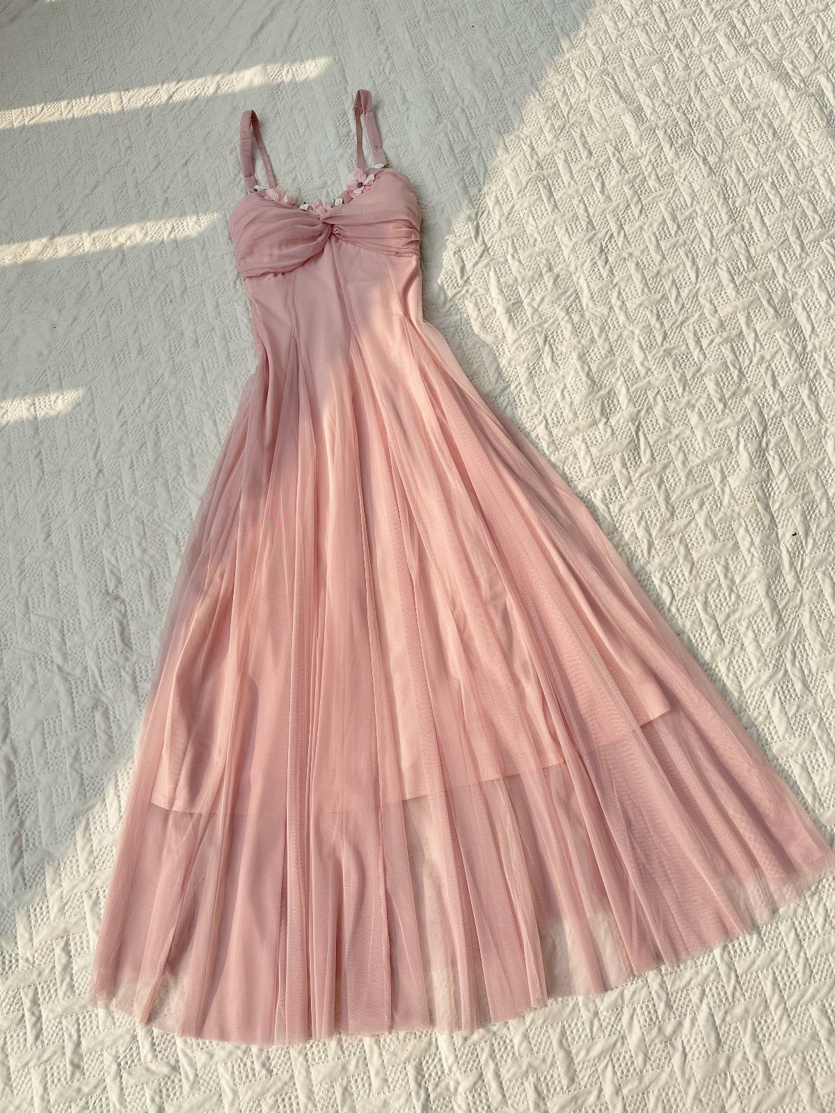 Dusty rose pink tulle midi dress laid flat on a white textured background.