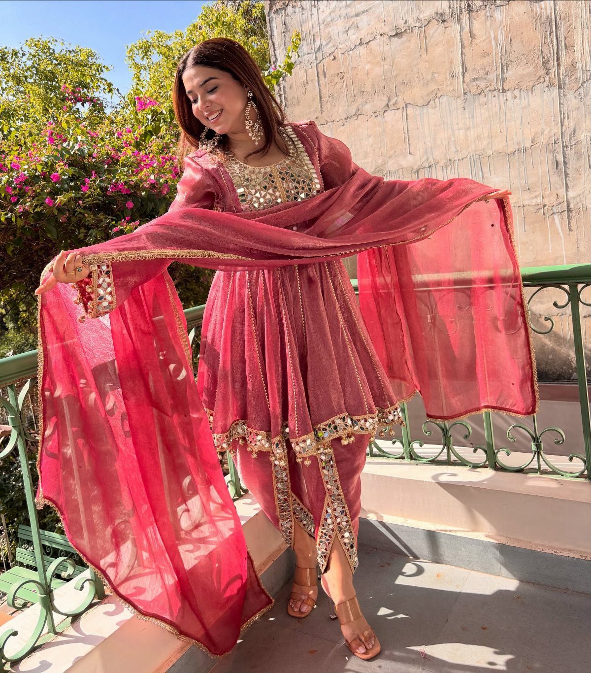 Woman in maroon dhoti style dress with gold embroidery and matching dupatta.