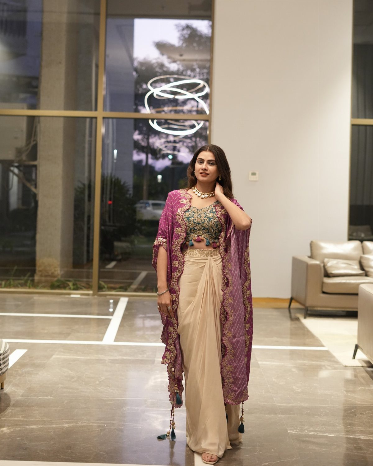 Woman wearing a fusion Indo-Western outfit with a purple cape and gold draped skirt.