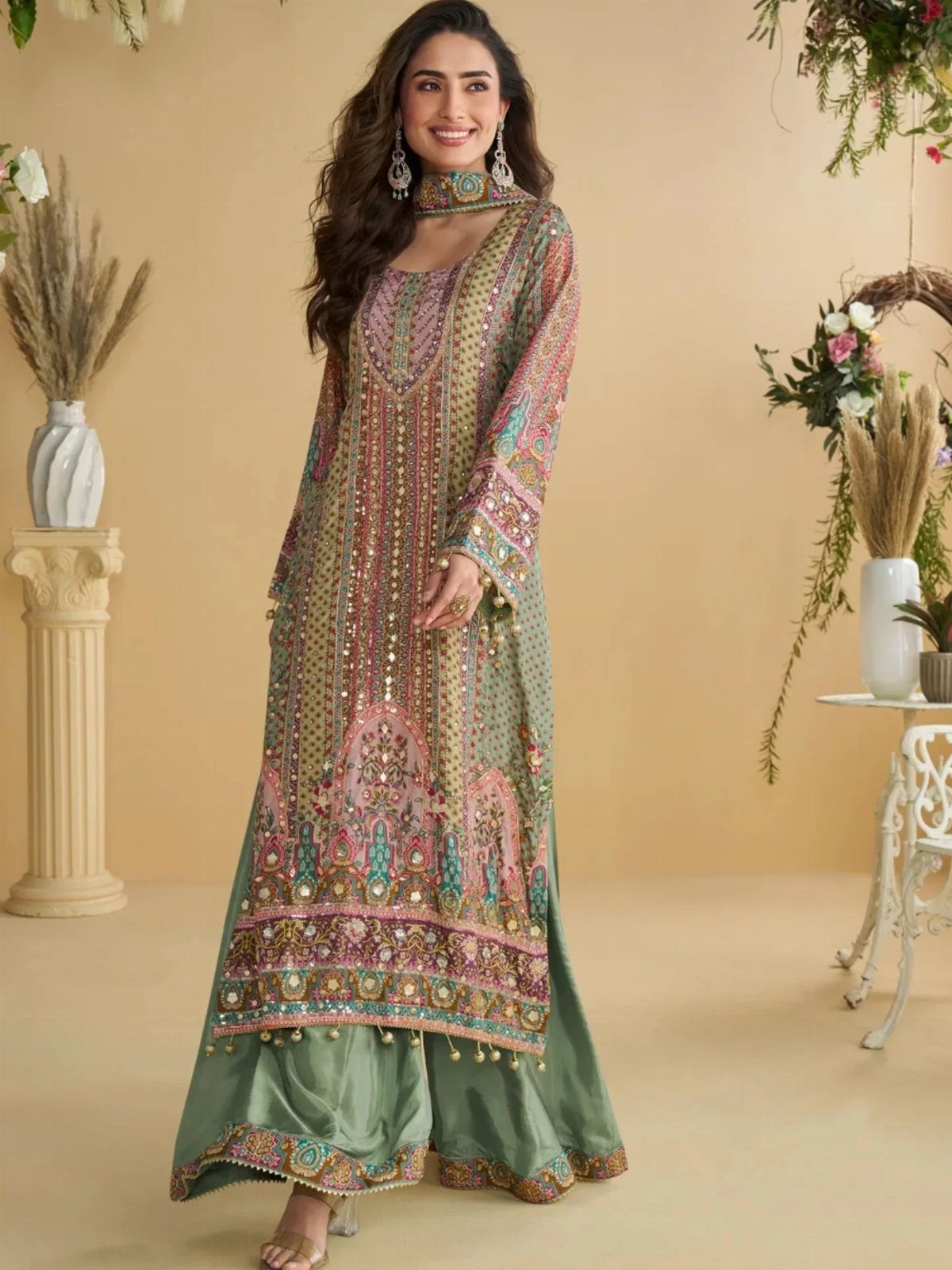 Woman wearing a multi-colored embroidered tunic with wide green palazzo pants.