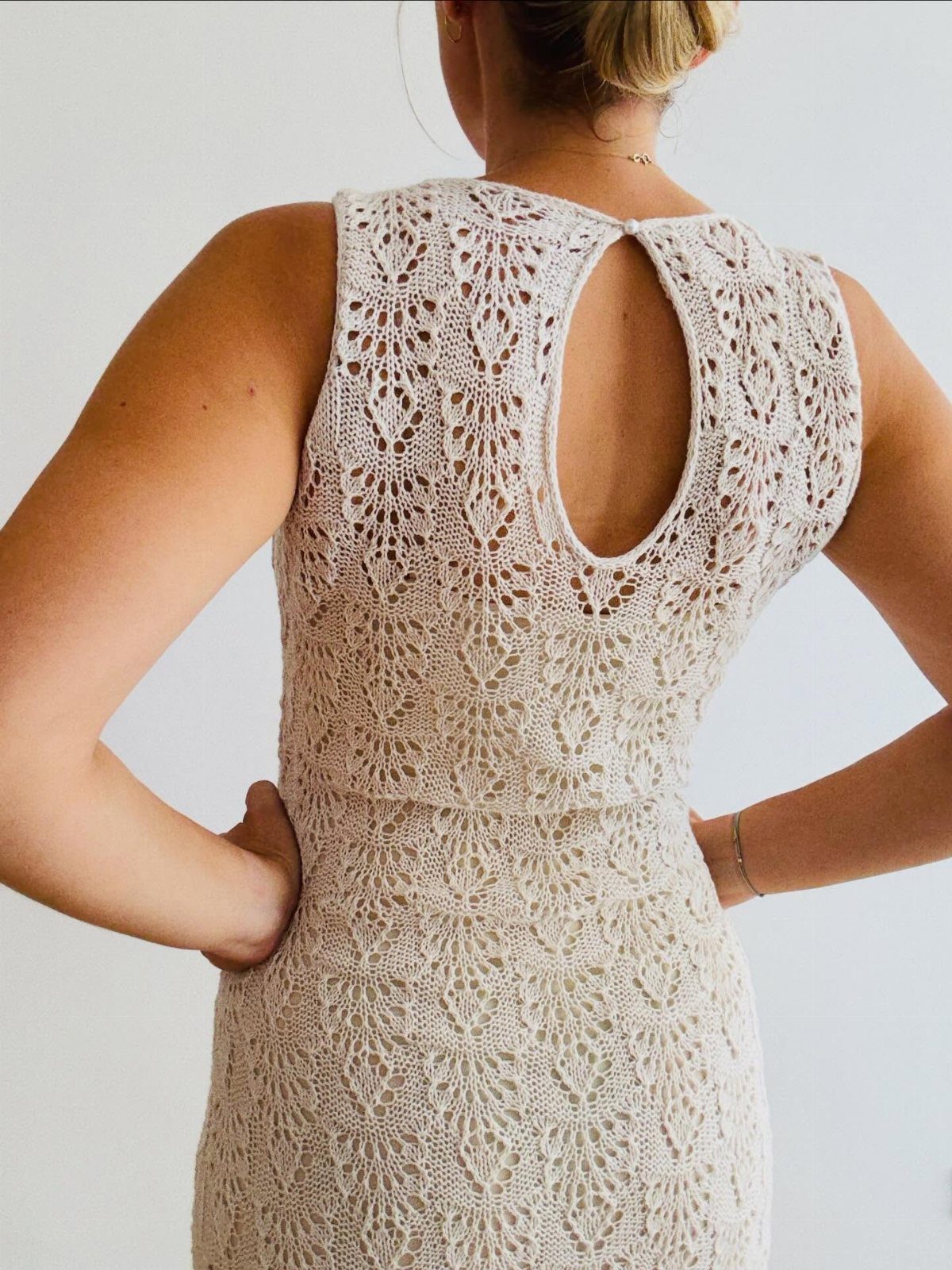 Woman wearing a cream crochet jumper dress with a keyhole back detail.