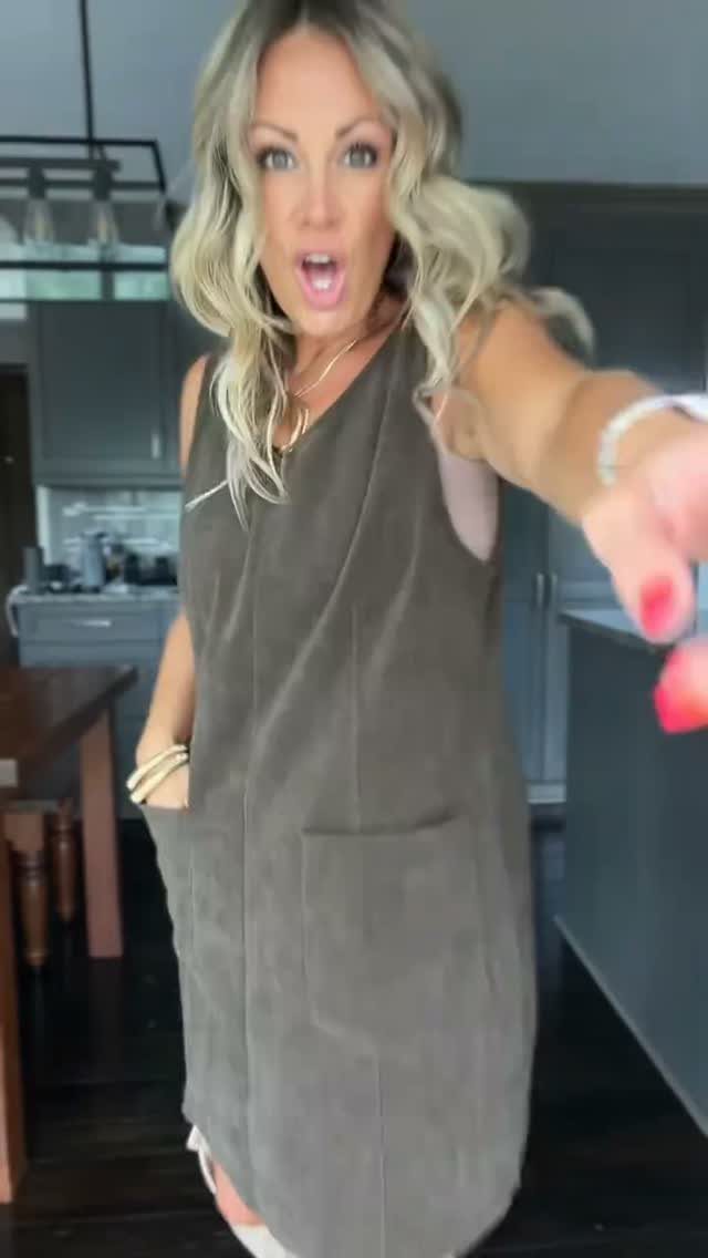 Woman wearing an olive green A-line jumper dress in a kitchen setting.