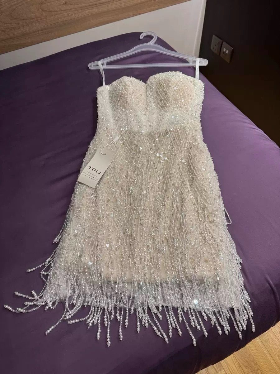 Knee-Length Cocktail Dress Styles: 15 Chic Ideas 14 Strapless white beaded cocktail dress with fringe hem hanging on a purple bed