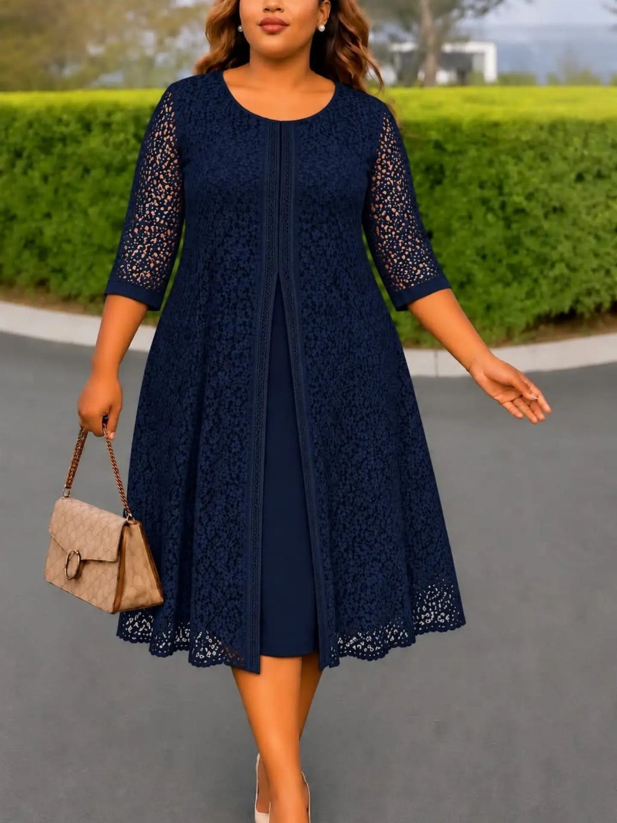 Knee-Length Cocktail Dress Styles: 15 Chic Ideas 4 Woman in a navy blue knee-length dress with a lace overlay and tan handbag.