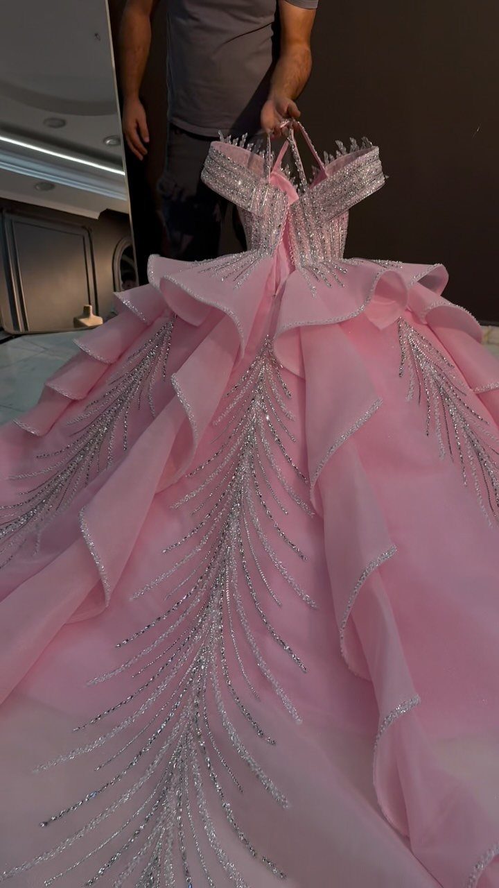 Pink off-the-shoulder ball gown with ruffles and silver glittery embroidery details.