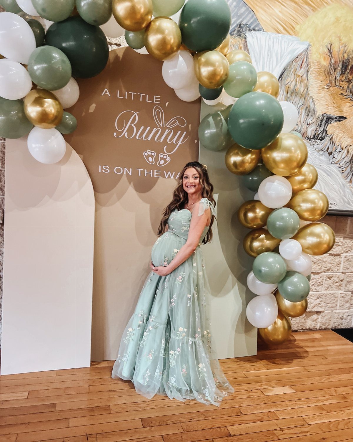 Pregnant woman in a light green floral tulle gown at a baby shower.