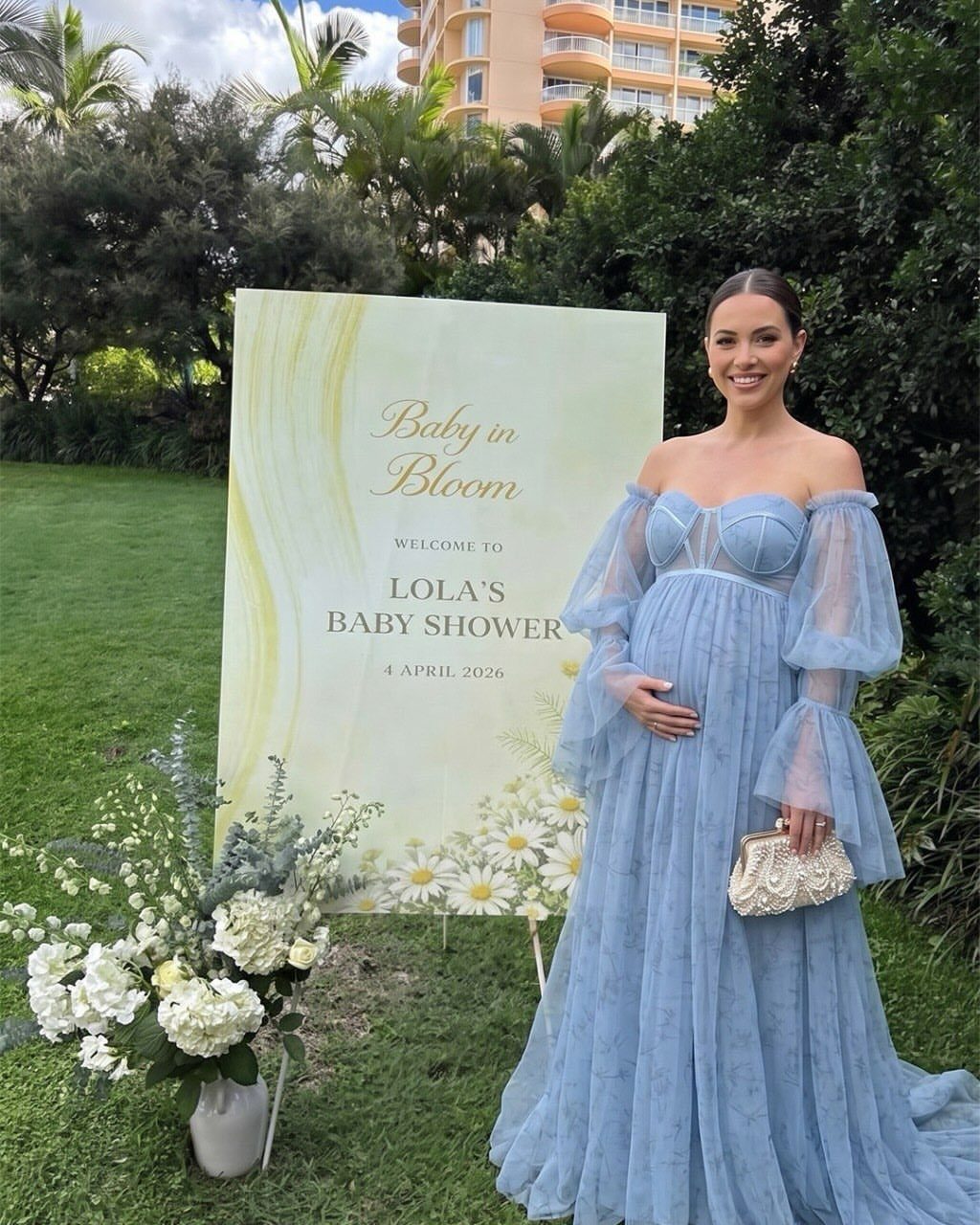 Pregnant woman in a light blue off-the-shoulder tulle maternity gown at baby shower.