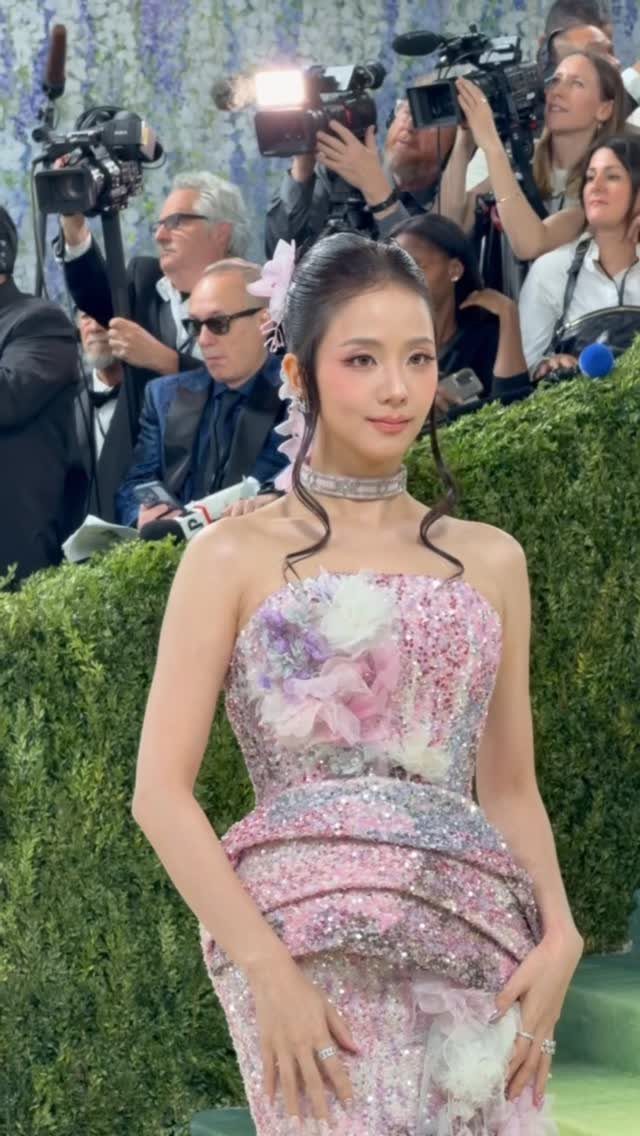 12 Met Gala Dresses That Defined Red Carpet Fashion 12 Woman in a sparkling pink floral gown posing on a red carpet event.