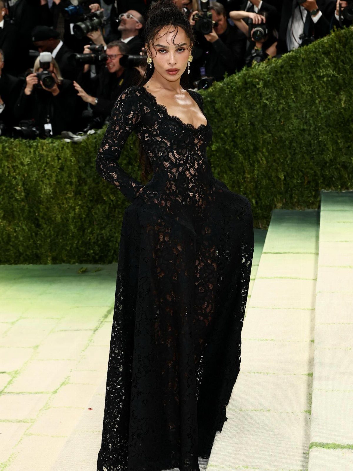 12 Met Gala Dresses That Defined Red Carpet Fashion 1 Woman in a long-sleeved black lace gown posing on a red carpet event.