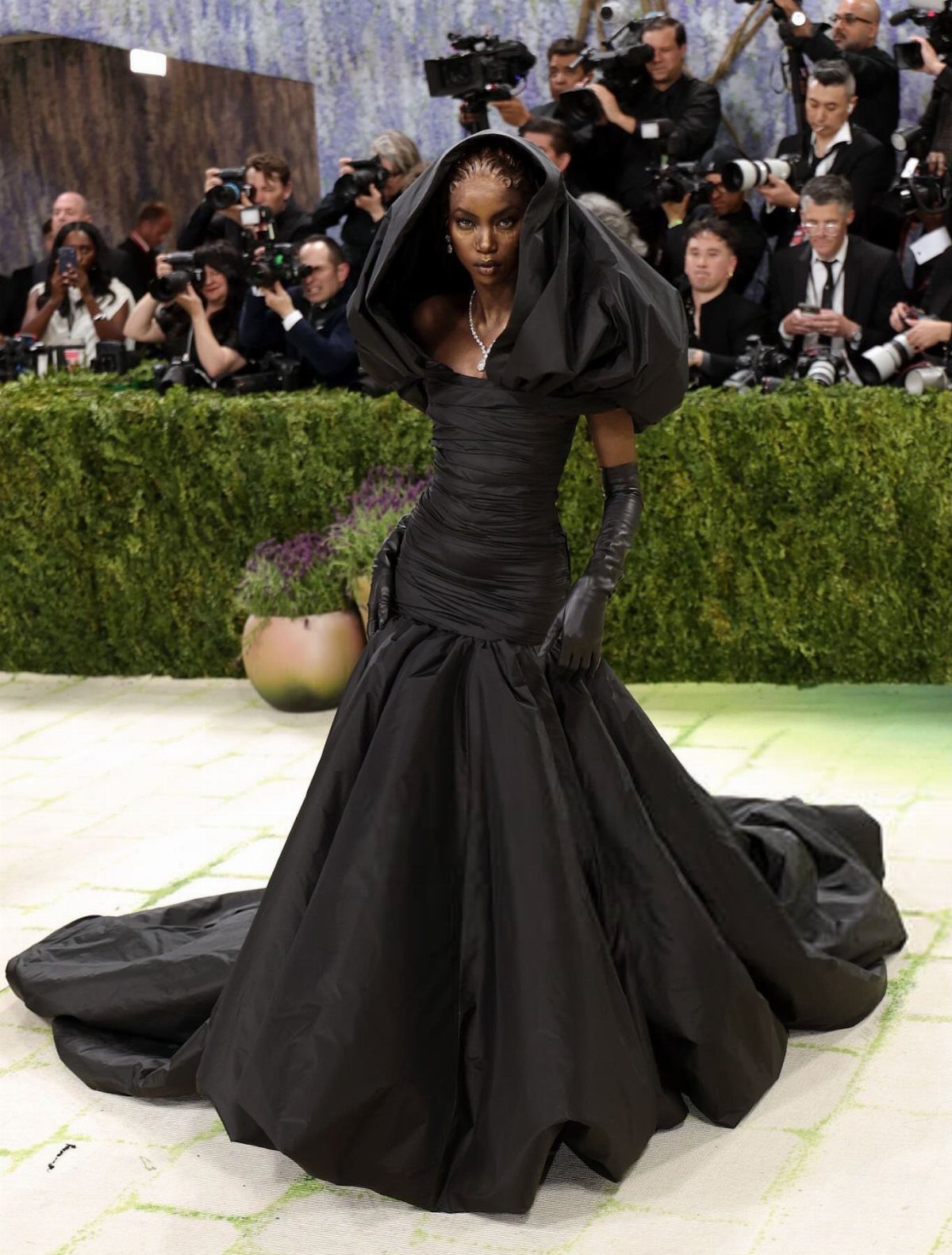 12 Met Gala Dresses That Defined Red Carpet Fashion 10 Woman in a voluminous black avant-garde gown with a large hood posing for photographers.