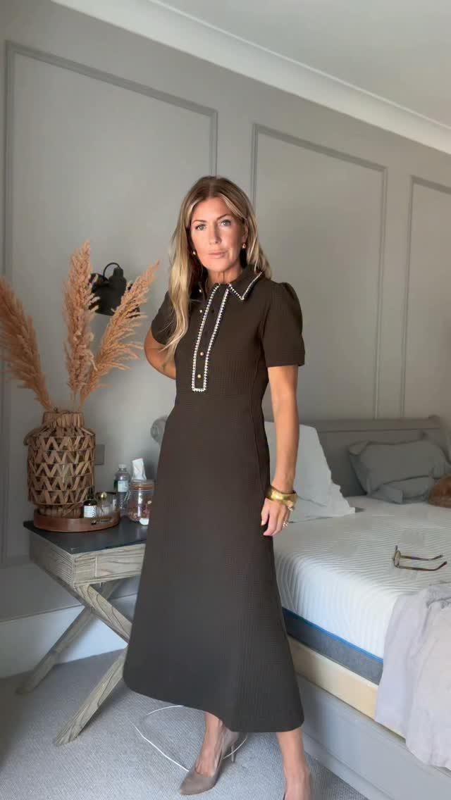 Woman wearing a dark brown midi dress with white trim in a bedroom