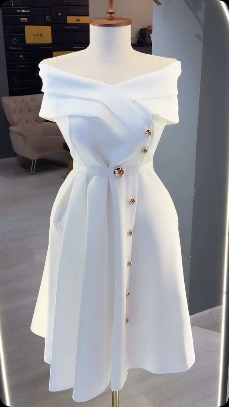 White off-the-shoulder midi dress with gold buttons on a white mannequin.