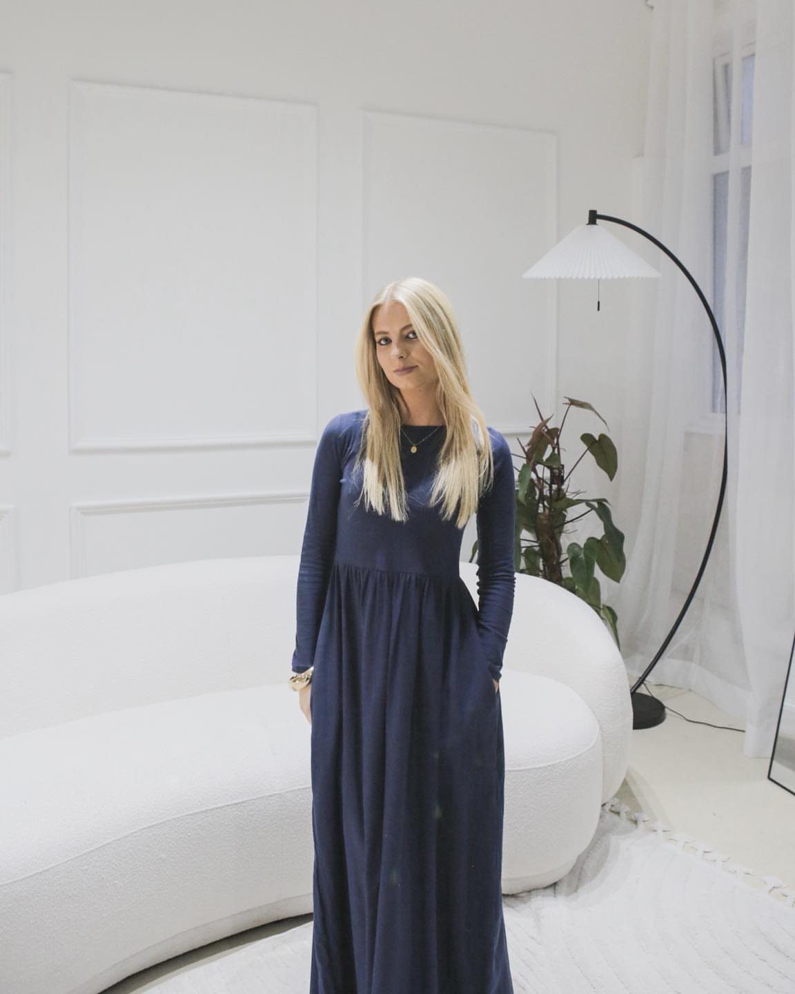 Petite Maxi Dresses in 10 Styles for Every Occasion 6 Blonde woman in a navy blue long-sleeved maxi dress standing in a white room.