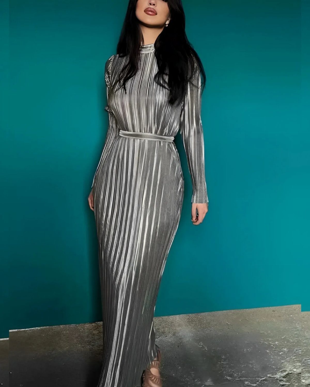 Petite Maxi Dresses in 10 Styles for Every Occasion 10 Woman wearing a silver metallic pleated maxi dress against a teal blue wall