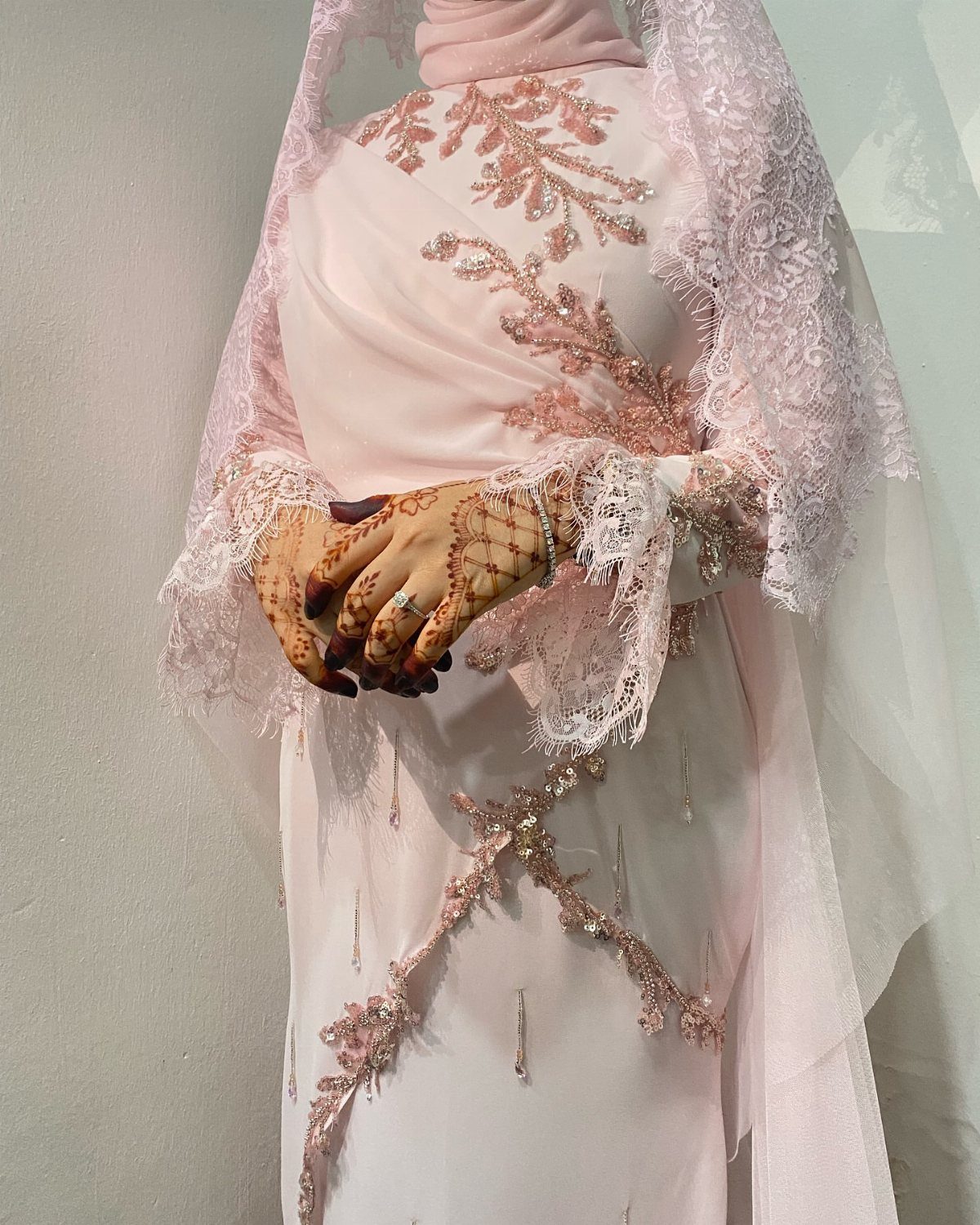 Light pink wedding gown with lace appliqués, matching hijab, and lace veil.