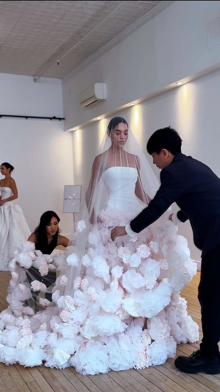 Woman in a white wedding dress with a voluminous pale pink floral petal skirt.