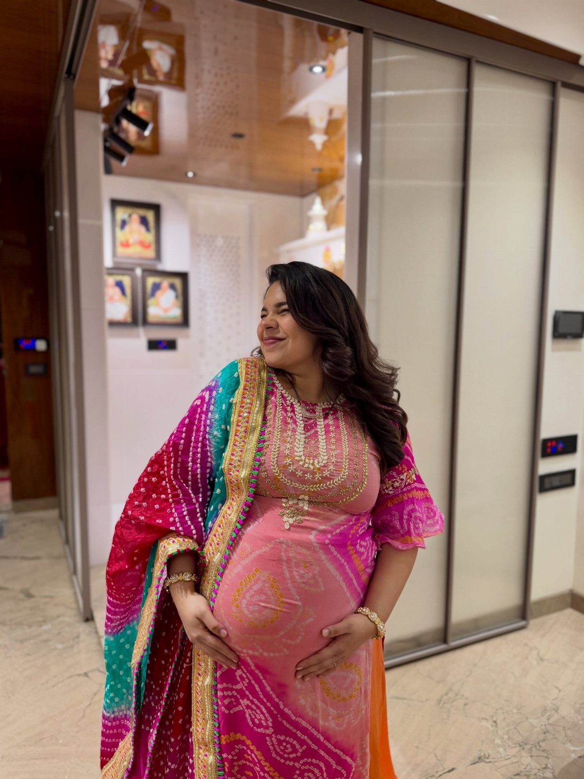 Pregnant woman wearing a pink and purple traditional Indian dress with gold embroidery.