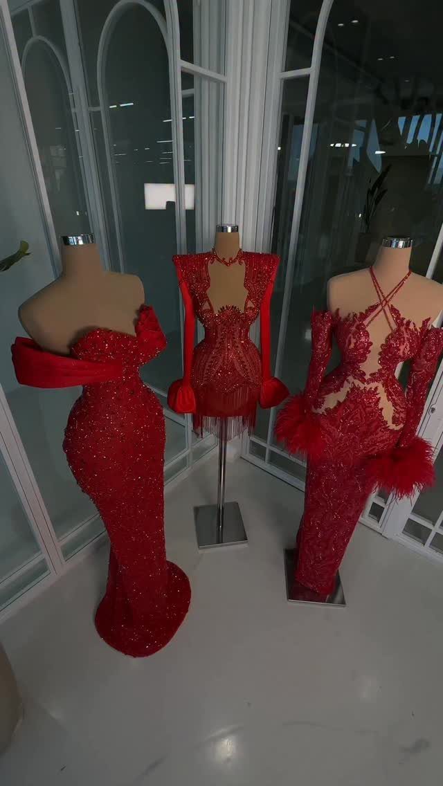 Three red sequined formal gowns displayed on mannequins in a white room.