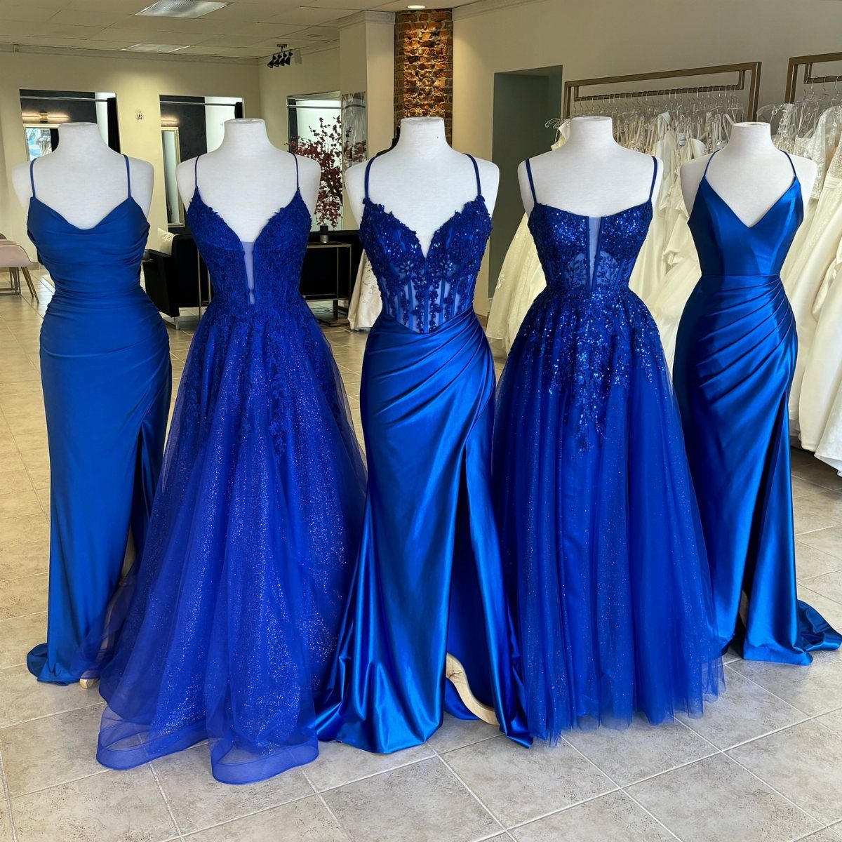 Royal Blue Colour Dress Styles: 7 Elegant Options to Try 1 Five royal blue gowns in different styles displayed on white mannequins in a shop.