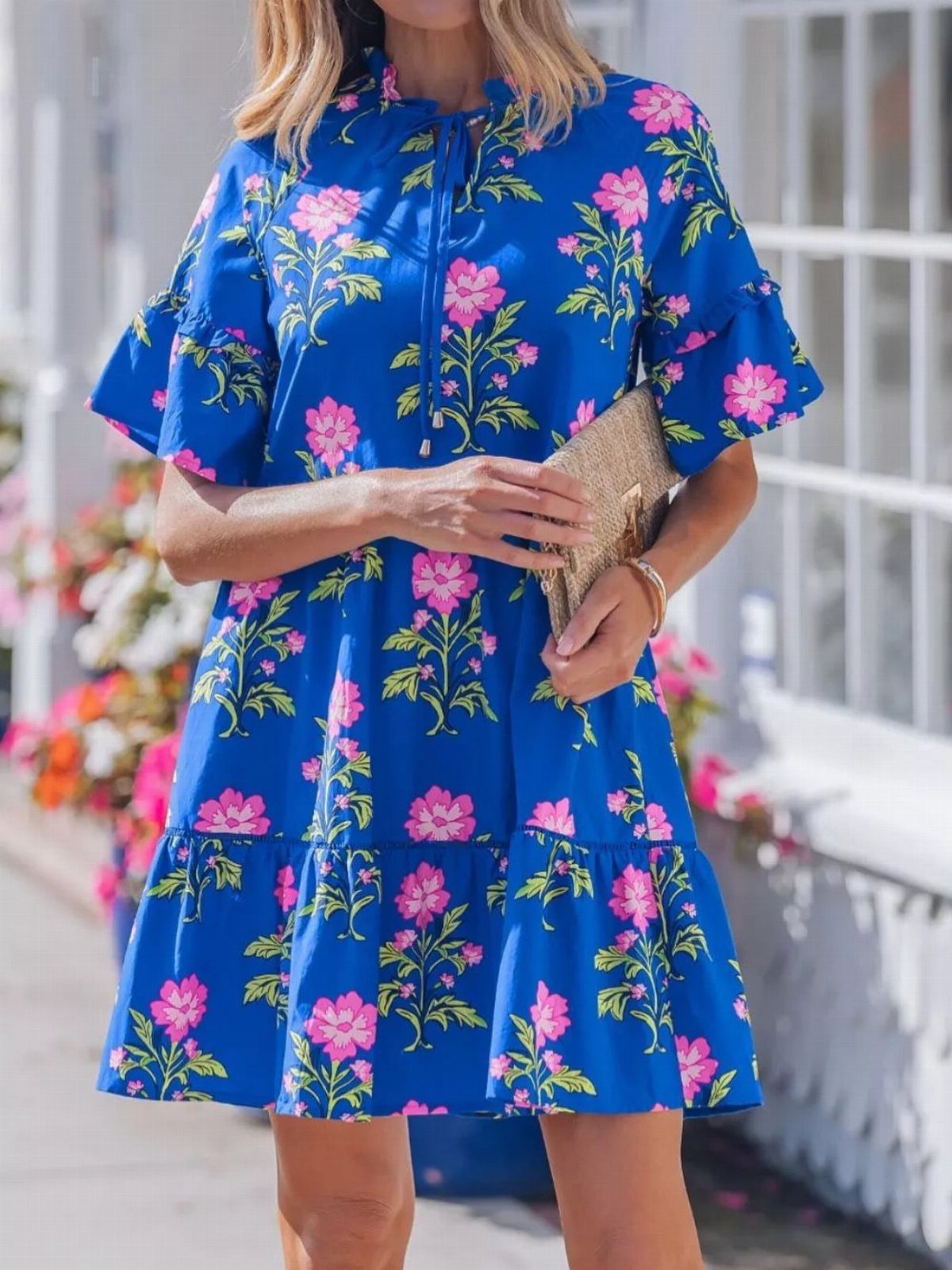 Royal Blue Colour Dress Styles: 7 Elegant Options to Try 4 Woman wearing a royal blue short-sleeved floral dress with a gold clutch bag.