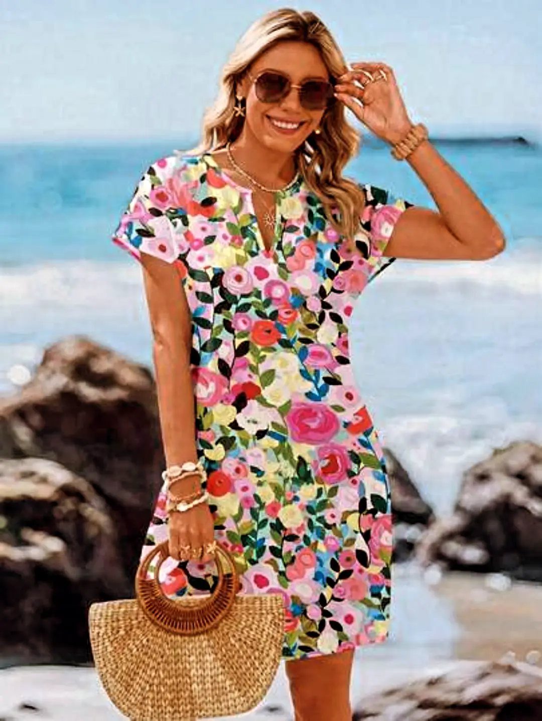 8 Short Summer Dresses Zara Shoppers Love Right Now 3 Woman in a colorful floral short V-neck dress posing on a rocky beach.