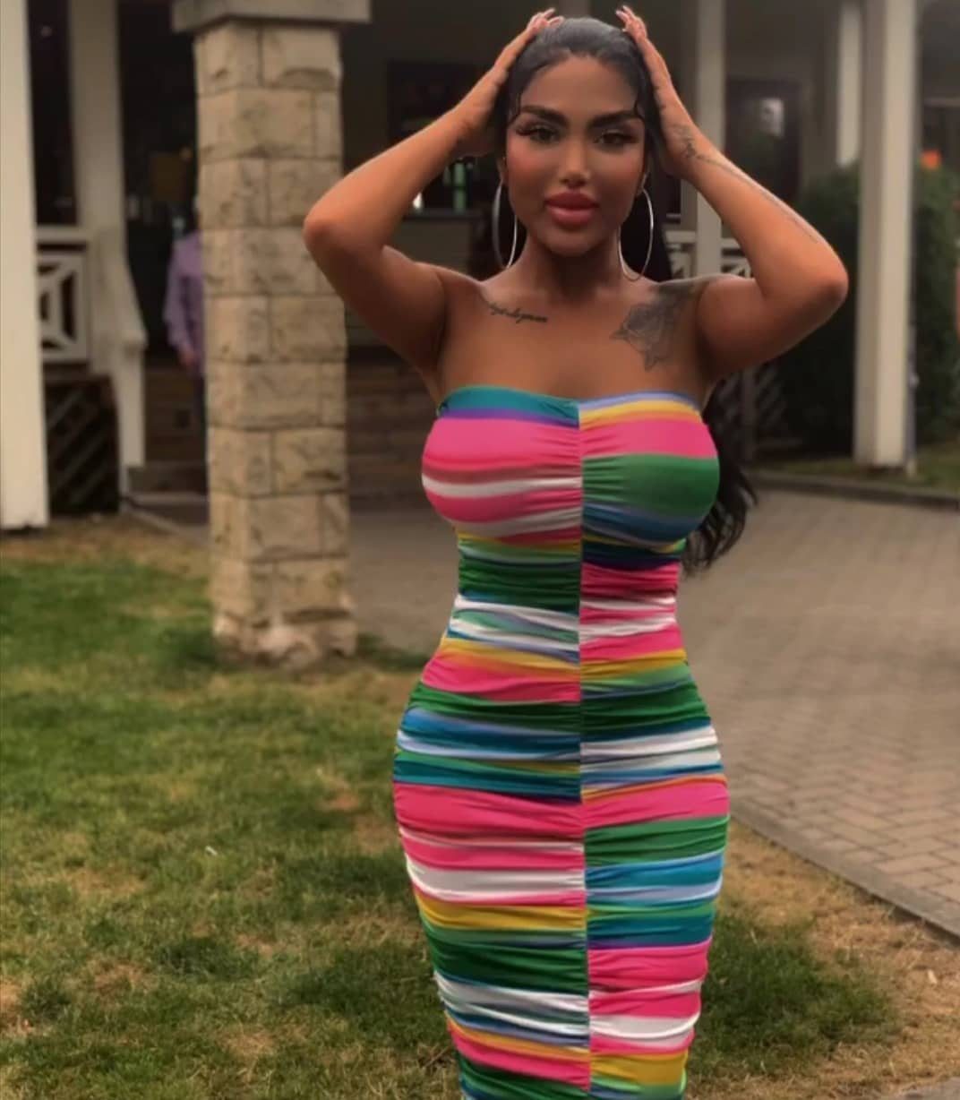 8 Short Summer Dresses Zara Shoppers Love Right Now 1 Woman wearing a colorful striped strapless bandeau mini dress posing outdoors on grass.