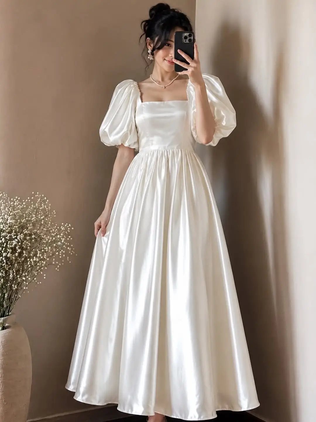 Simplistic Wedding Dress Ideas: 6 Elegant Styles to Consider 2 Woman in a plain white satin wedding dress with puff sleeves taking a selfie.