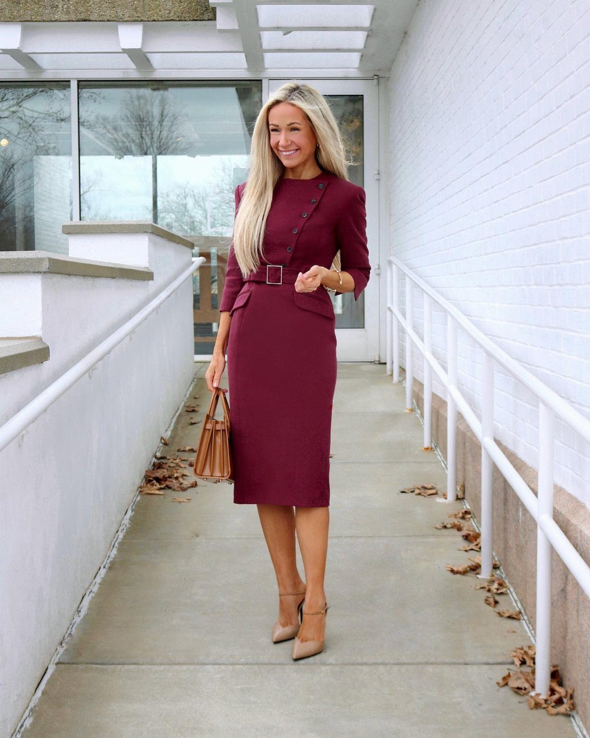 9 Stylish Work Dresses That Keep You Polished All Day 8 Woman in a maroon belted work dress with tan heels on a walkway.