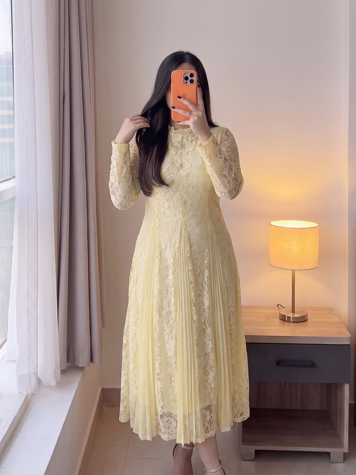 Woman in a pale yellow lace dress with long sleeves and flared skirt.